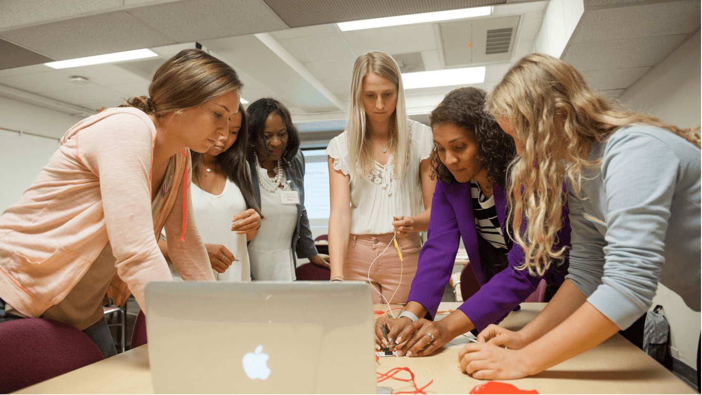 a group of women looking at a laptop