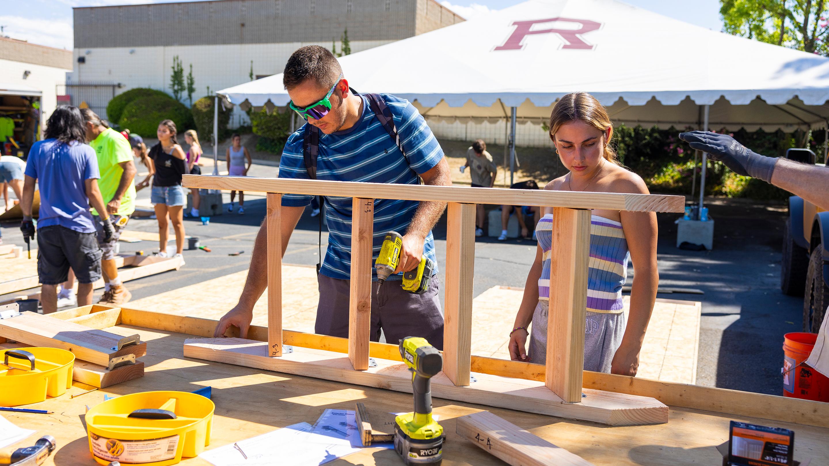a man and woman working on a wood piece