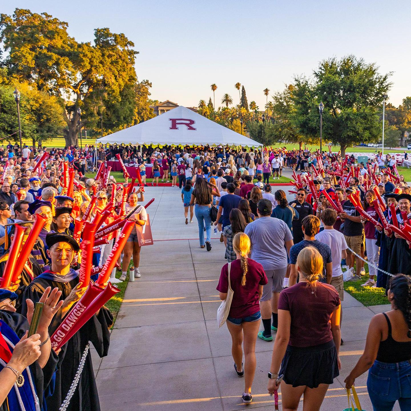 a group of people walking on a sidewalk with a white tent