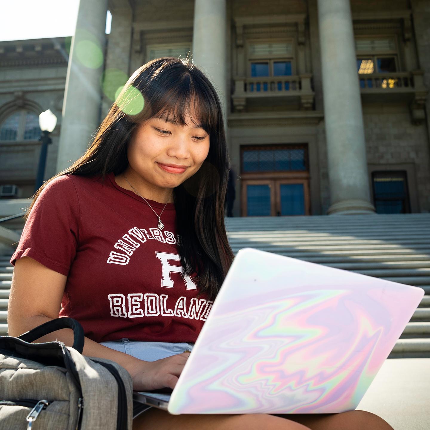 a woman sitting on steps with a laptop
