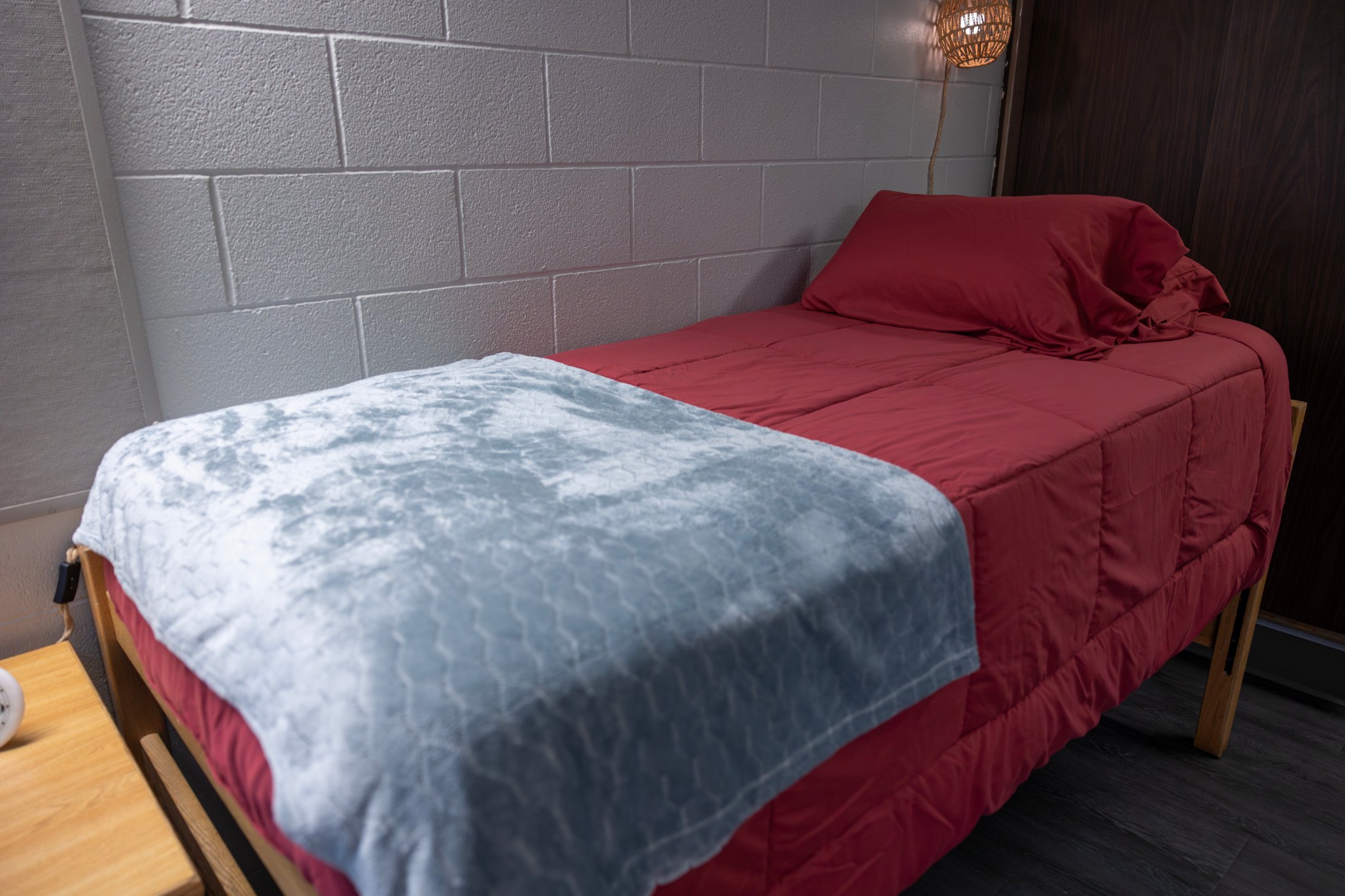 a bed with a red blanket and a lamp