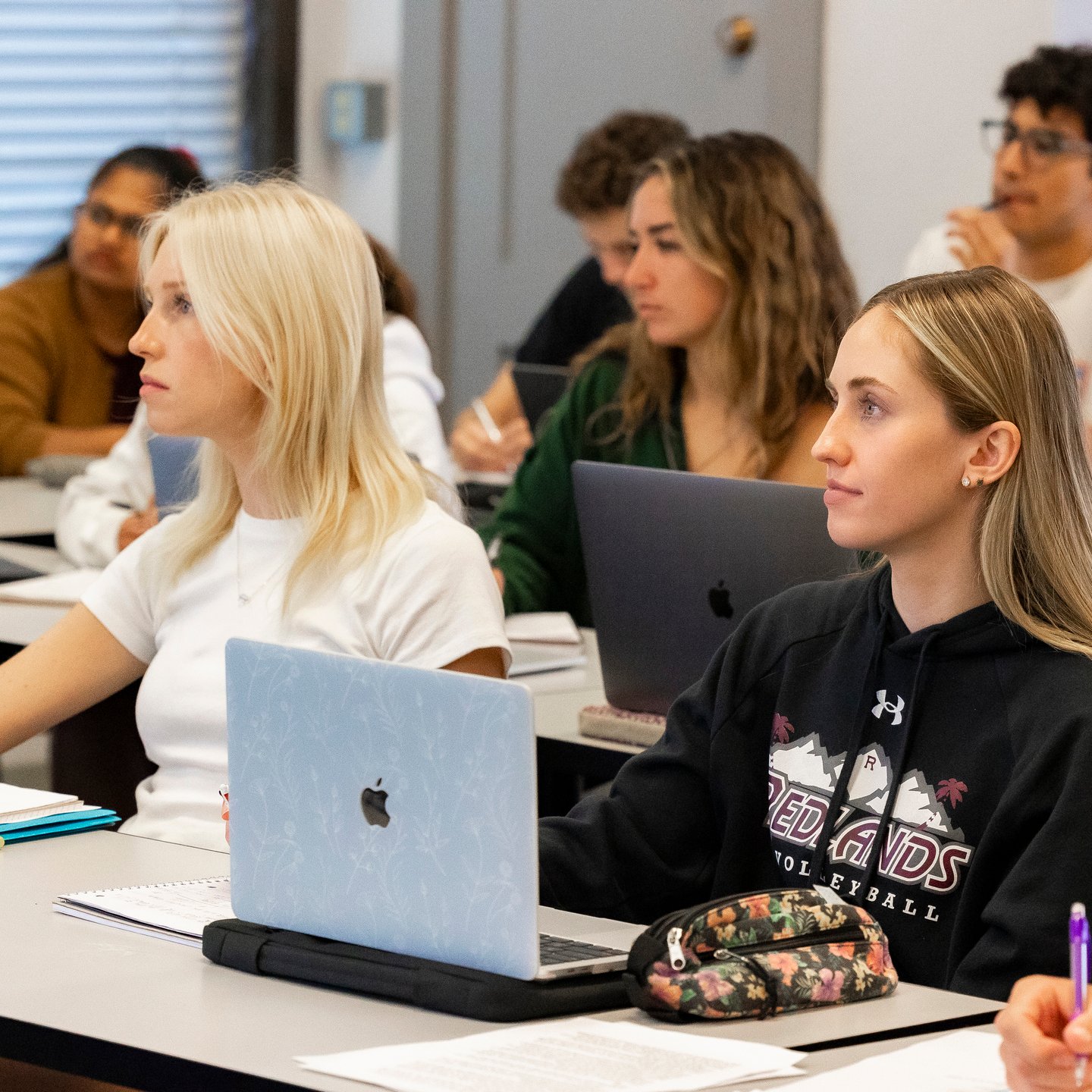 a group of people sitting at tables with laptops