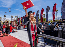 Graduate raising their diploma in celebration.