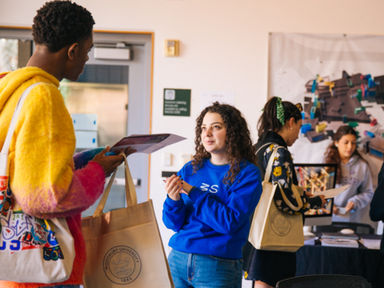 Two students speaking to each other, with more students grouped behind them interacting.