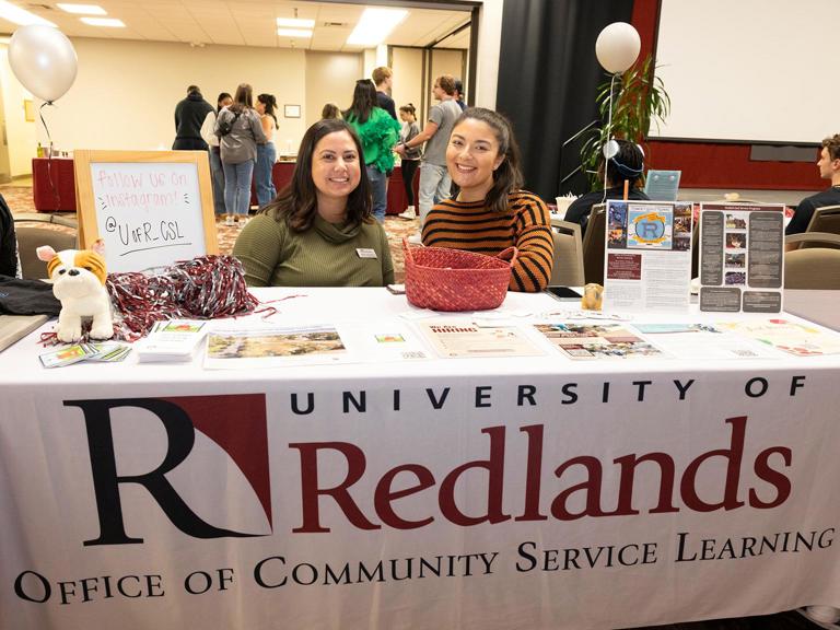 Two Community Service Learning members sitting and advertising internships.