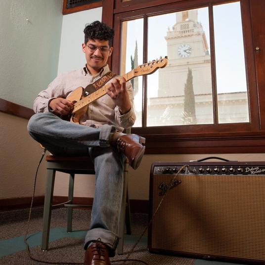 Guitar player practicing the strings in the School of Music.