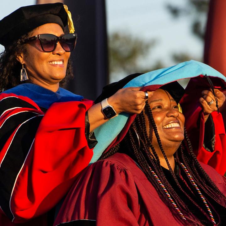 School of Education graduate student receiving their diploma in commencement.