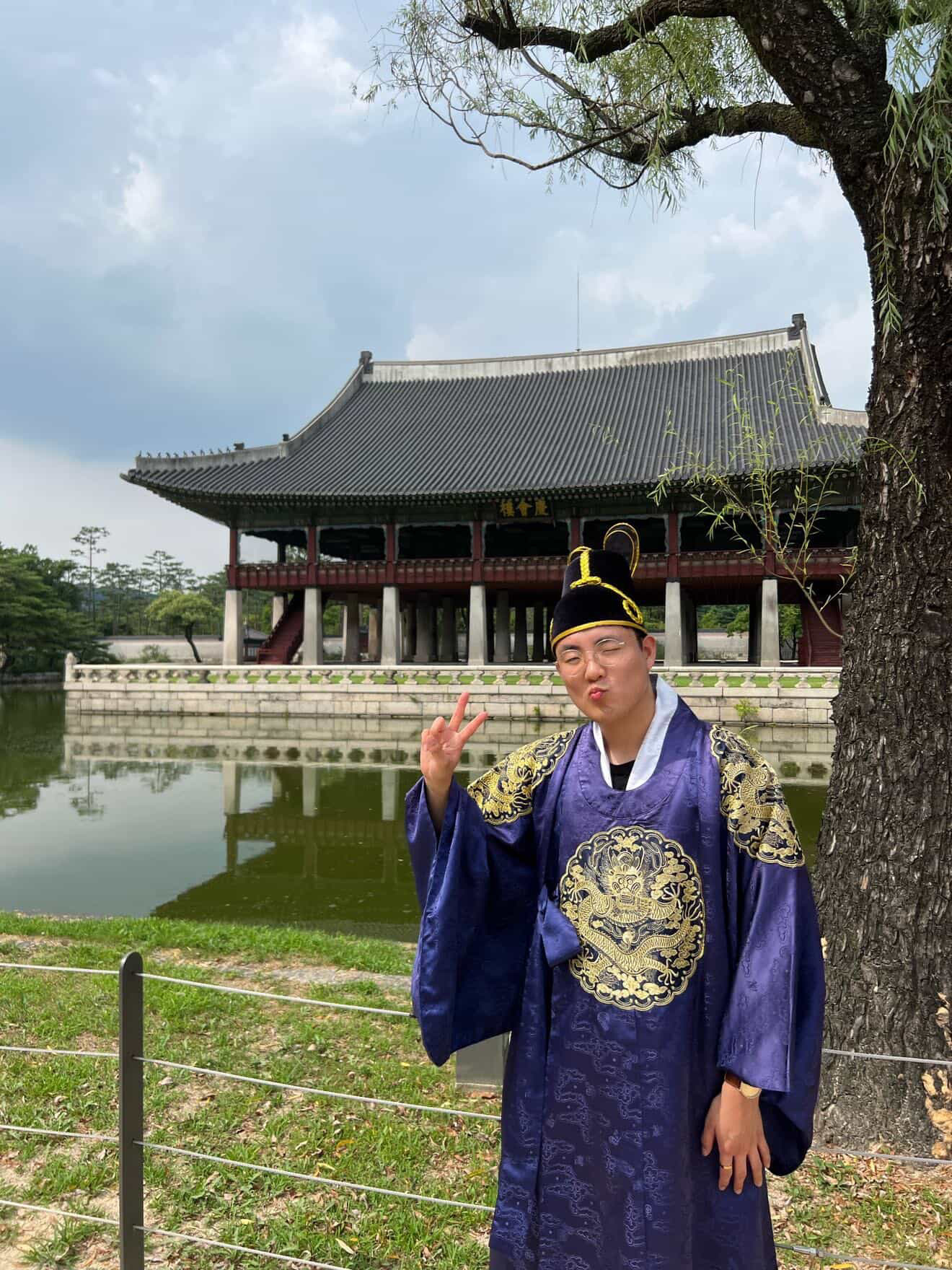 a man in a blue robe and hat standing in front of a building