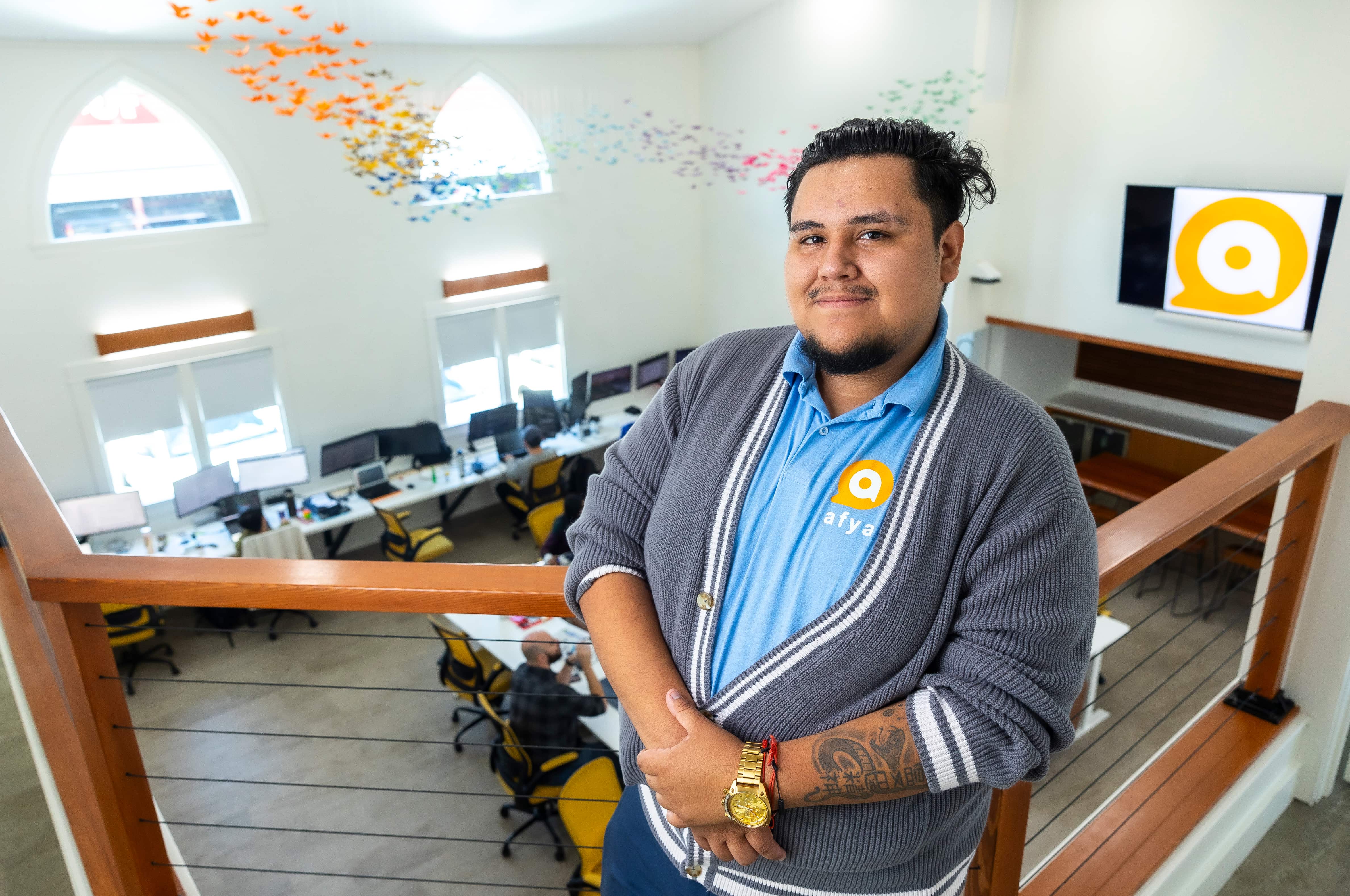 a man standing on a railing in a room with chairs and tables